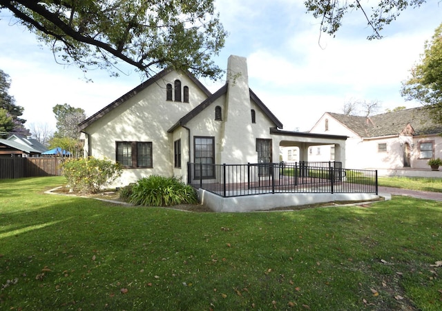 rear view of property featuring a patio, fence, a yard, stucco siding, and a chimney