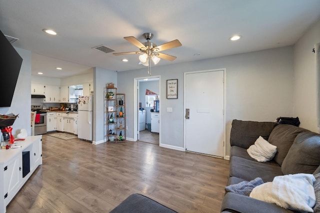 living area with washer and dryer, visible vents, wood finished floors, and recessed lighting