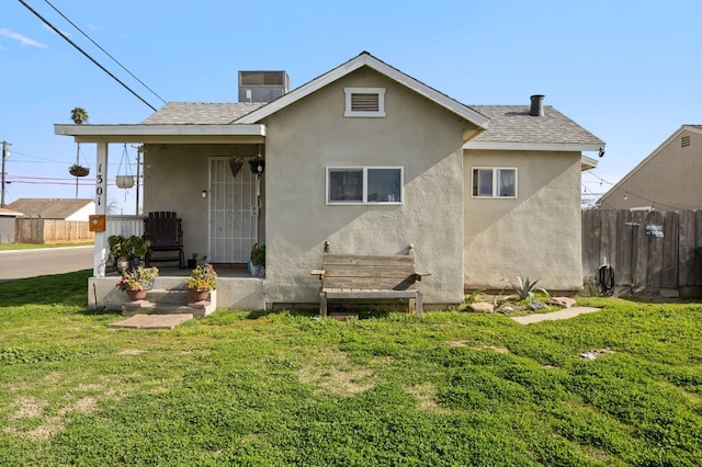 back of property featuring a yard, fence, roof with shingles, and stucco siding