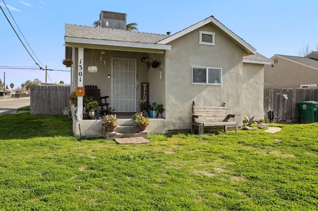 exterior space featuring stucco siding, a chimney, a front lawn, and fence