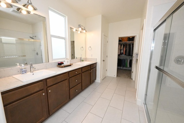 full bath with double vanity, a stall shower, a spacious closet, and a sink