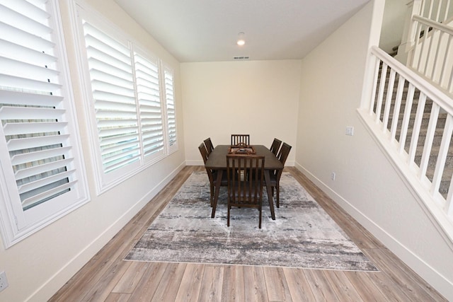 dining area with visible vents, baseboards, wood finished floors, and stairs