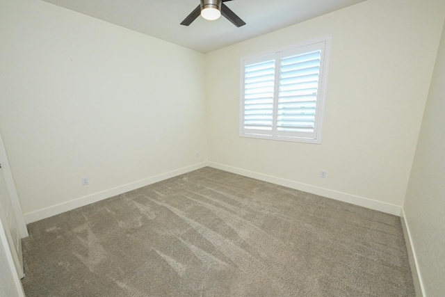 empty room with carpet flooring, a ceiling fan, and baseboards