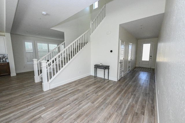 foyer entrance featuring baseboards, wood finished floors, and stairs