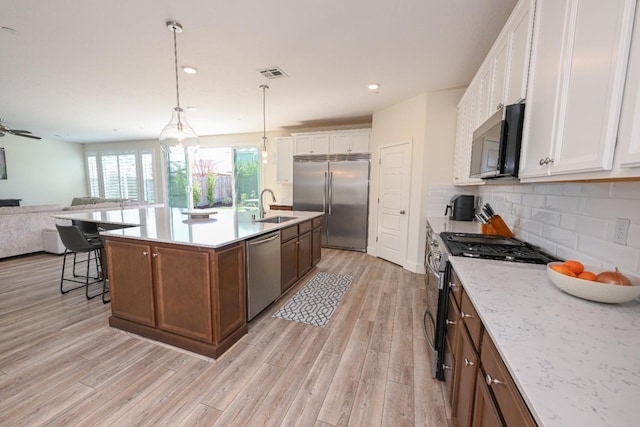 kitchen with tasteful backsplash, visible vents, open floor plan, stainless steel appliances, and a sink