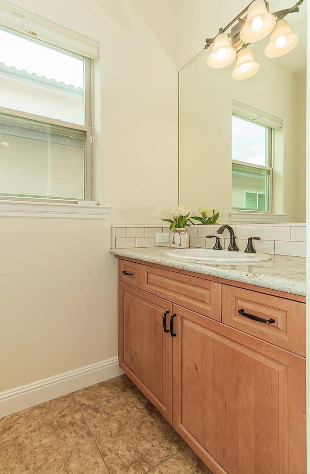 bathroom featuring healthy amount of natural light, vanity, baseboards, and tile patterned flooring