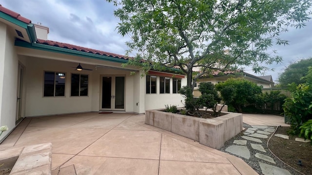 rear view of property with a patio area, stucco siding, french doors, and a tile roof