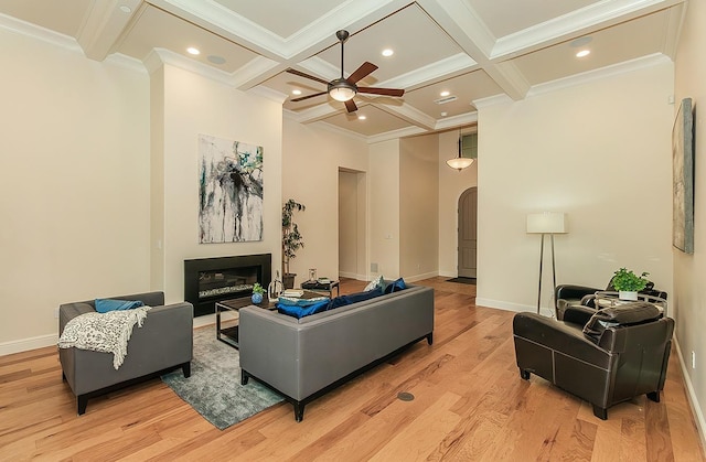 living room with coffered ceiling, light wood-style flooring, arched walkways, a glass covered fireplace, and beamed ceiling