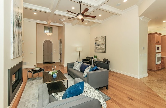 living area with light wood finished floors, beamed ceiling, coffered ceiling, and crown molding