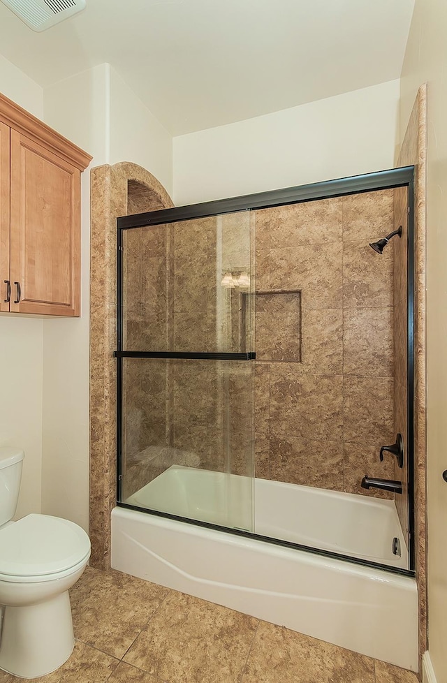 bathroom with toilet, visible vents, and bath / shower combo with glass door