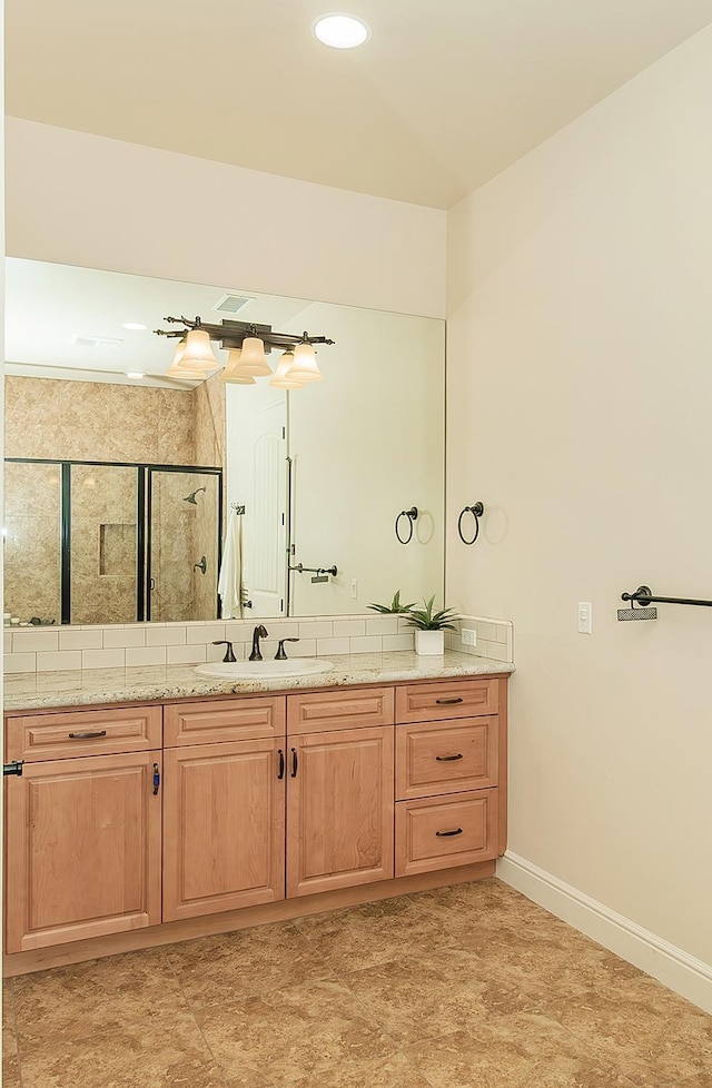 bathroom with visible vents, baseboards, vanity, and a shower stall