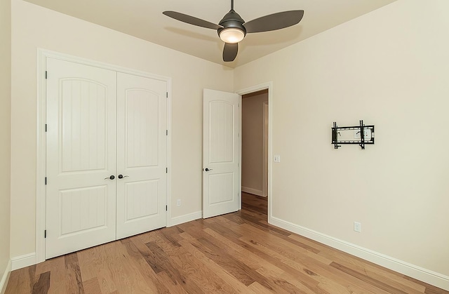 unfurnished bedroom featuring a closet, ceiling fan, light wood-type flooring, and baseboards