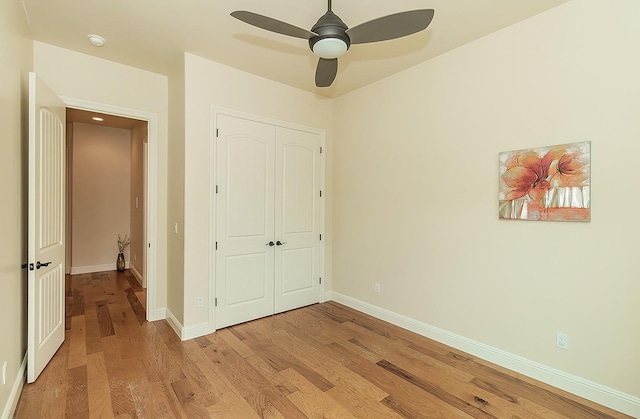 unfurnished bedroom with ceiling fan, a closet, baseboards, and wood finished floors