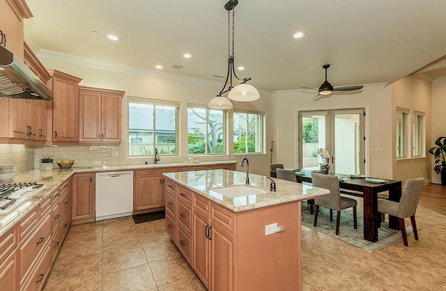 kitchen featuring white appliances, a center island with sink, ornamental molding, a sink, and tasteful backsplash