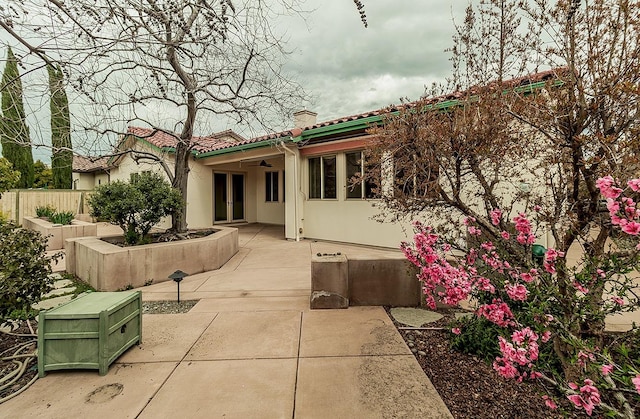 back of house featuring fence, ceiling fan, a chimney, stucco siding, and a patio area