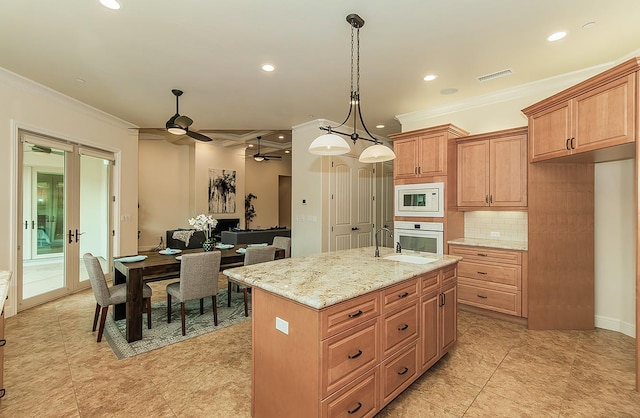 kitchen featuring visible vents, a center island with sink, tasteful backsplash, white appliances, and crown molding