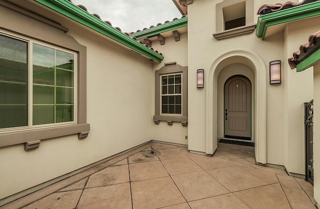 view of exterior entry featuring stucco siding and a patio