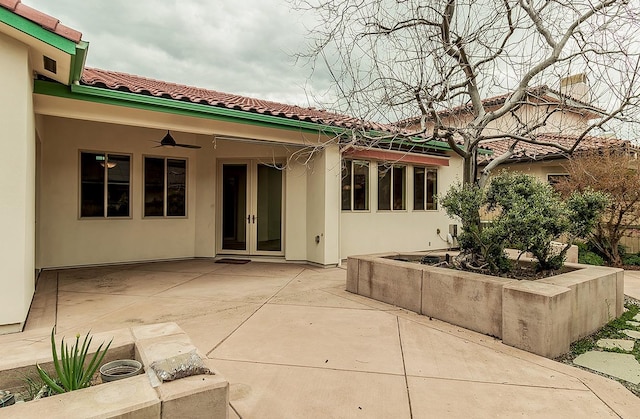 rear view of property with ceiling fan, a tiled roof, stucco siding, french doors, and a patio area