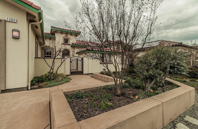 view of front of house with a tiled roof, stucco siding, and a gate