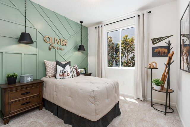 bedroom with a decorative wall, baseboards, and light carpet