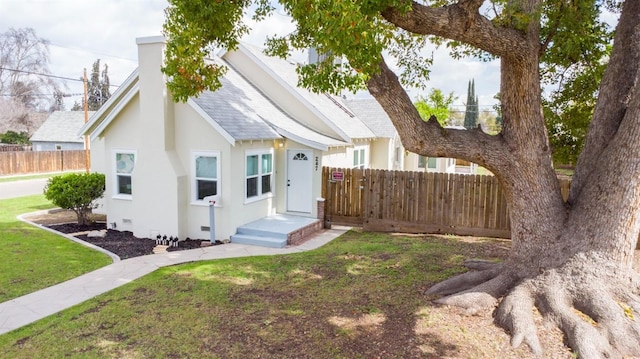 view of front of property with stucco siding, a shingled roof, a front yard, and fence