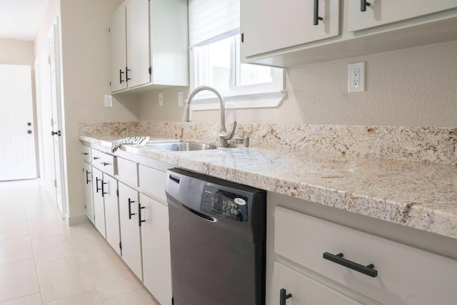 kitchen featuring light stone countertops, dishwasher, light tile patterned floors, white cabinets, and a sink