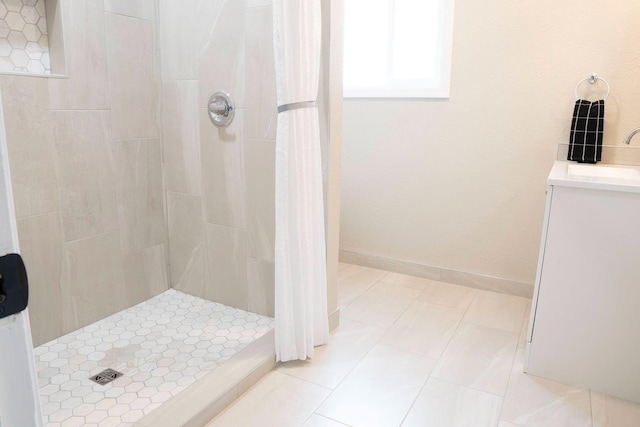 bathroom featuring baseboards, a stall shower, and a sink