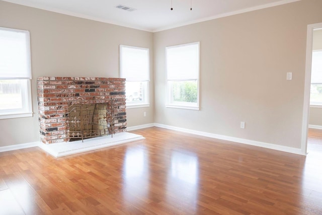 unfurnished living room with ornamental molding, wood finished floors, visible vents, and baseboards