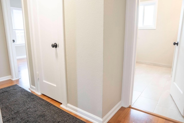 hall with light wood-type flooring and baseboards