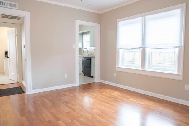 spare room featuring a sink, visible vents, light wood-style floors, and ornamental molding