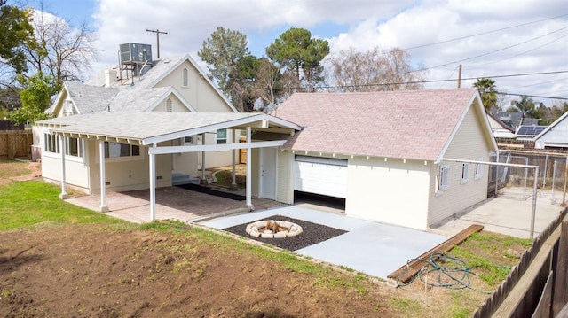 view of front of home featuring fence, a fire pit, roof with shingles, a garage, and a patio area