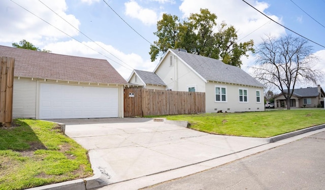 view of property exterior with a lawn, a detached garage, roof with shingles, and fence