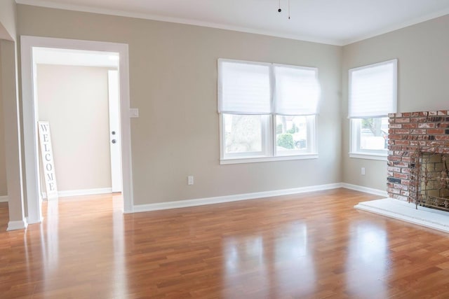 unfurnished living room with a fireplace, light wood-type flooring, baseboards, and crown molding