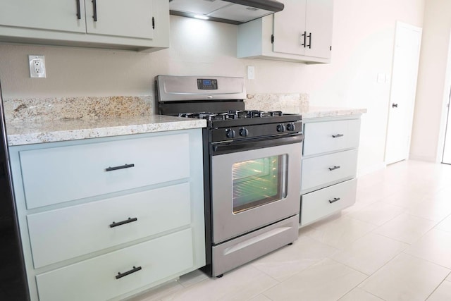 kitchen featuring stainless steel gas range oven, light stone counters, under cabinet range hood, and white cabinetry