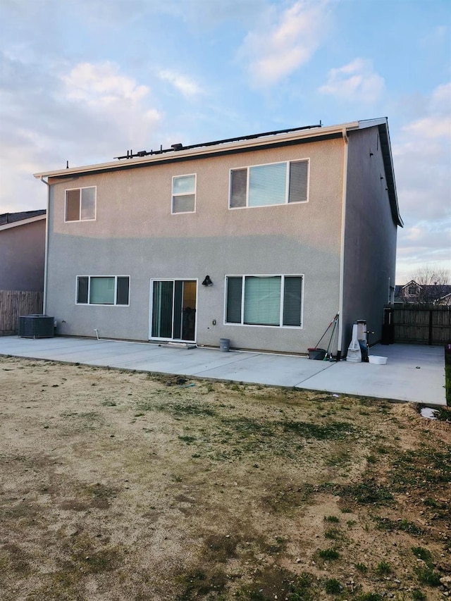 rear view of property with central AC unit, a patio area, fence, and stucco siding