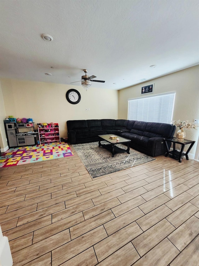 living room with a ceiling fan, a textured ceiling, and wood tiled floor