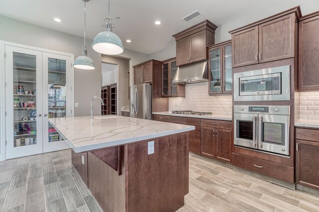 301 Pinnacle Dr W, Madera, CA 93636 - kitchen with stainless steel appliances, under cabinet range hood, a sink, a kitchen island with sink, and light stone counters