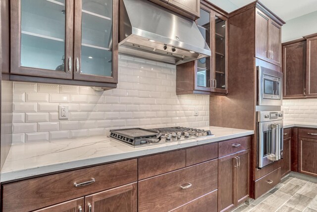 301 Pinnacle Dr W, Madera, CA 93636 - kitchen with stainless steel appliances, exhaust hood, decorative backsplash, light stone countertops, and glass insert cabinets