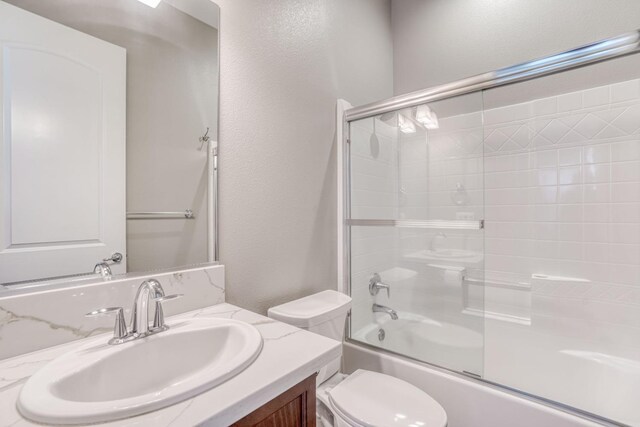 301 Pinnacle Dr W, Madera, CA 93636 - bathroom featuring toilet, vanity, combined bath / shower with glass door, and a textured wall