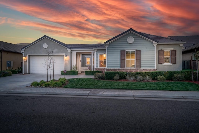 ranch-style home featuring brick siding, a tile roof, concrete driveway, stucco siding, and a garage