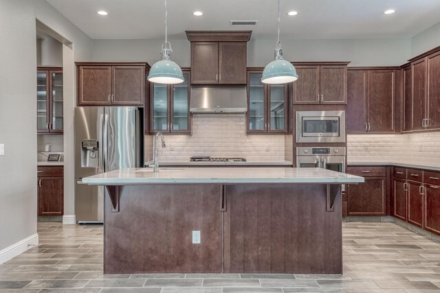 301 Pinnacle Dr W, Madera, CA 93636 - kitchen with appliances with stainless steel finishes, under cabinet range hood, wood tiled floors, a center island with sink, and recessed lighting