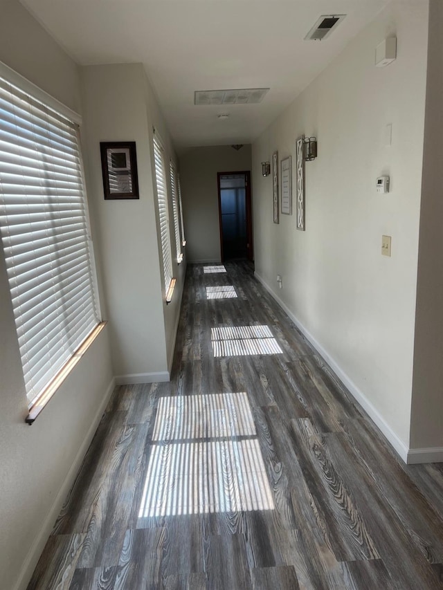 hall with wood finished floors, visible vents, and baseboards