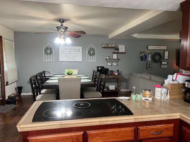 kitchen with tile countertops, brown cabinetry, ceiling fan, dark wood-type flooring, and black electric stovetop