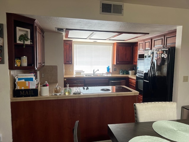 kitchen with visible vents, a peninsula, a sink, black fridge with ice dispenser, and tasteful backsplash