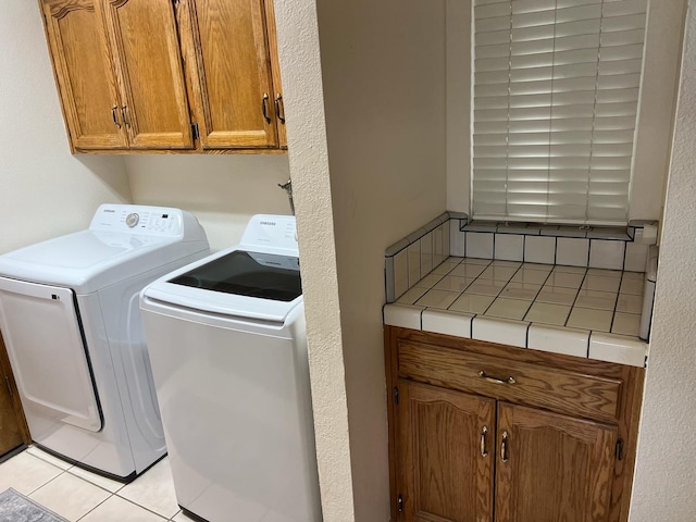 laundry area featuring cabinet space, light tile patterned flooring, and washing machine and dryer