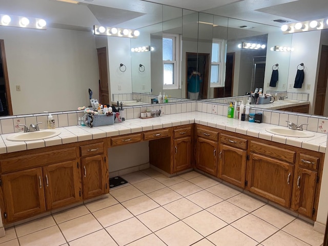 full bath with a sink, visible vents, double vanity, and tile patterned floors