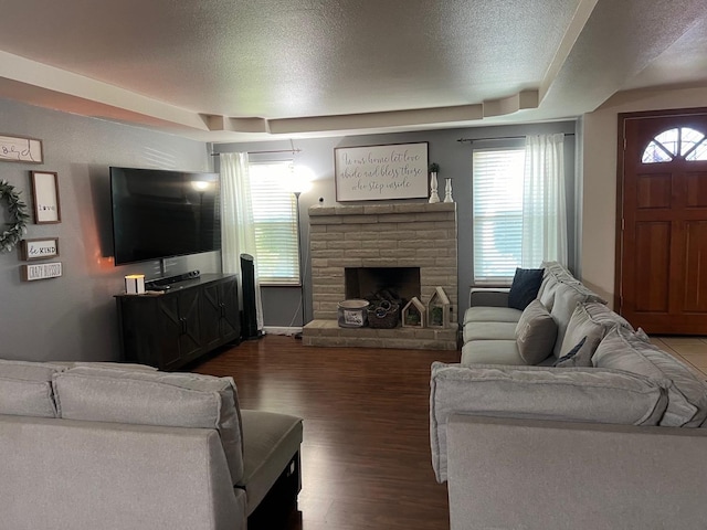 living area featuring a textured ceiling, a fireplace with raised hearth, and wood finished floors