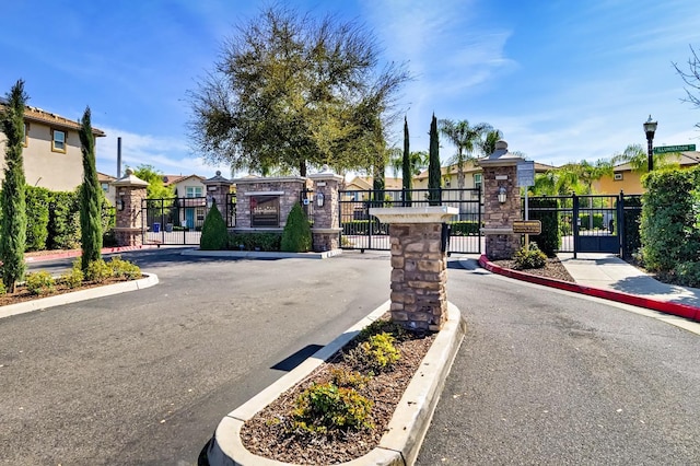 view of road with street lights, a gate, a residential view, and a gated entry