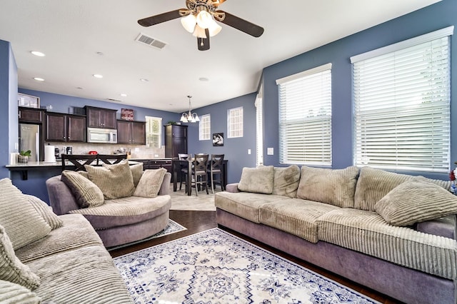 living area featuring recessed lighting, visible vents, dark wood-style floors, and ceiling fan with notable chandelier