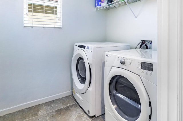 clothes washing area with washer and dryer, stone finish flooring, baseboards, and laundry area